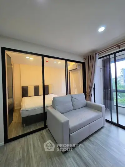 Modern apartment with glass-walled bedroom and cozy living area, featuring a balcony with a view.