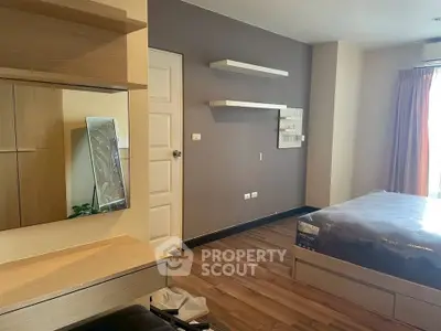 Modern bedroom with wooden flooring and stylish furniture, featuring a cozy bed and decorative shelves.