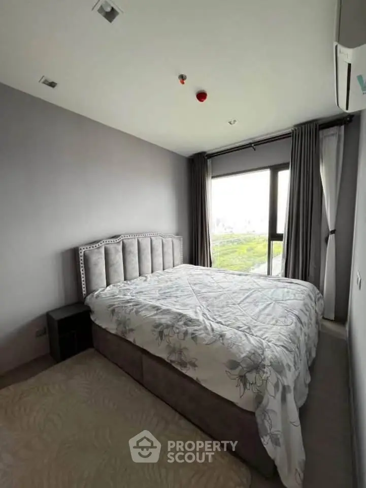 Modern bedroom with large window and stylish bed in a high-rise apartment.