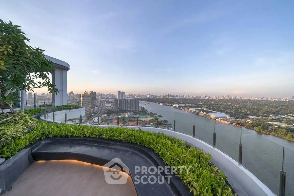 Stunning rooftop view with lush greenery overlooking a river and city skyline.