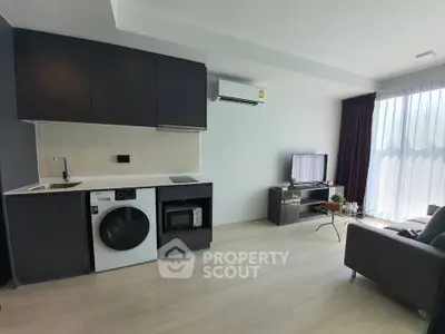 Modern living room with integrated kitchen featuring sleek appliances and stylish furniture.