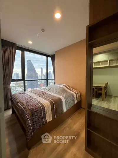 Modern bedroom with city view, featuring large windows and stylish decor in urban apartment.