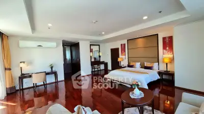 Luxurious bedroom with polished wooden floors, elegant decor, and ample natural light.