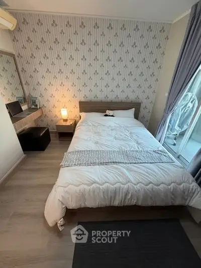 Cozy bedroom with stylish wallpaper and natural light, perfect for relaxation and comfort.