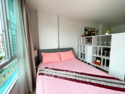 Cozy bedroom with pink bedding and large window offering pool view, perfect for relaxation.