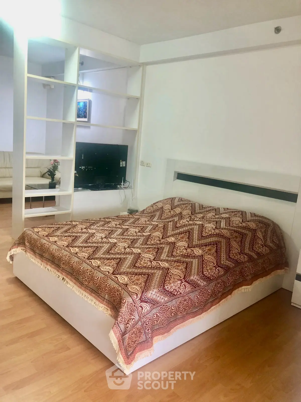 Spacious bedroom with elegant decor and open layout, featuring a cozy bed and stylish shelving.