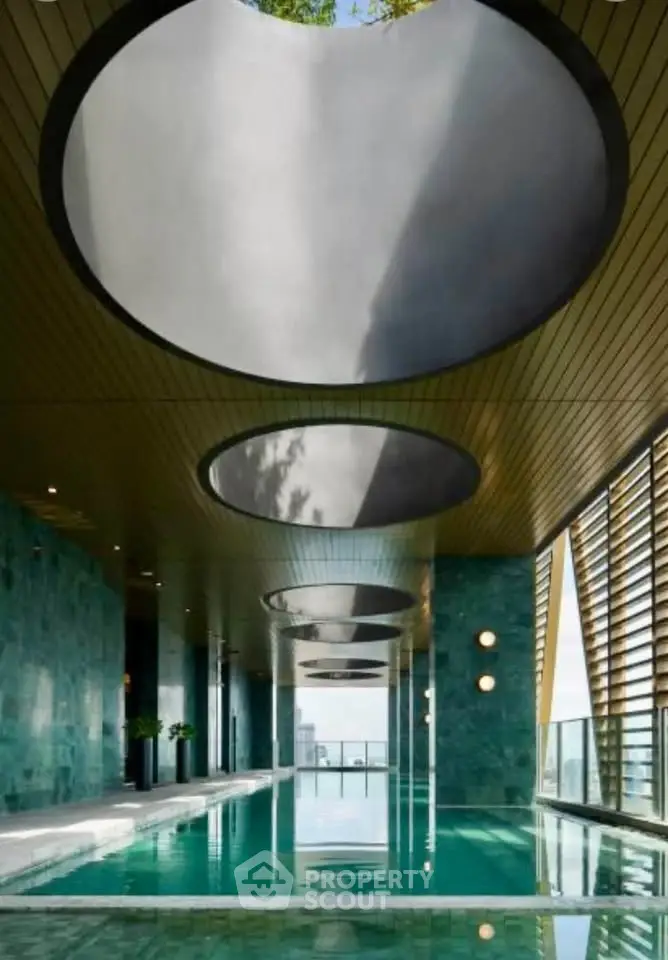 Luxurious indoor pool with modern design and skylights in upscale building.