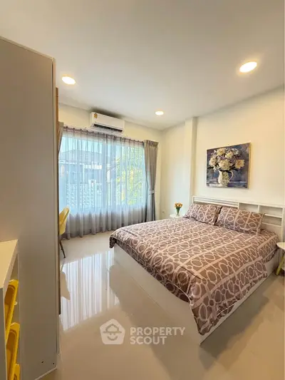 Spacious bedroom with large window and modern decor in a stylish apartment.