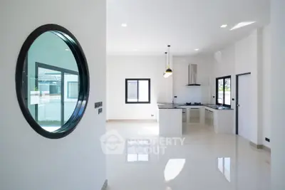 Modern open-plan kitchen with sleek design and large windows in a bright, spacious home.