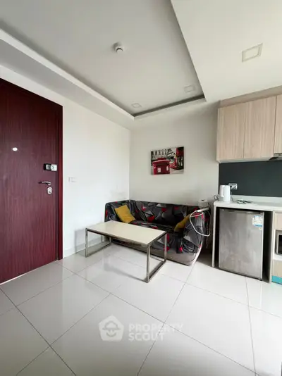 Modern apartment living room with sleek furniture and compact kitchen area.