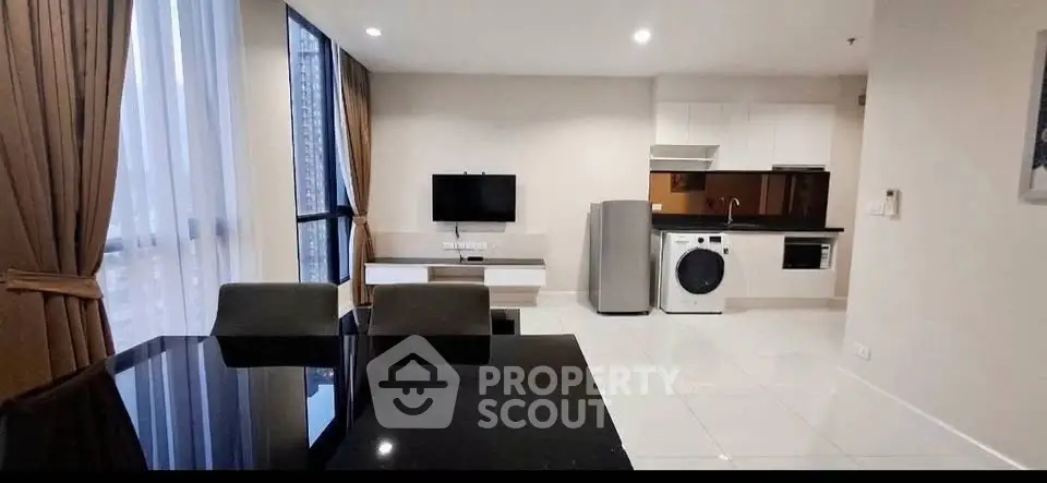 Modern open-plan living room with kitchen, featuring sleek appliances and elegant dining area.