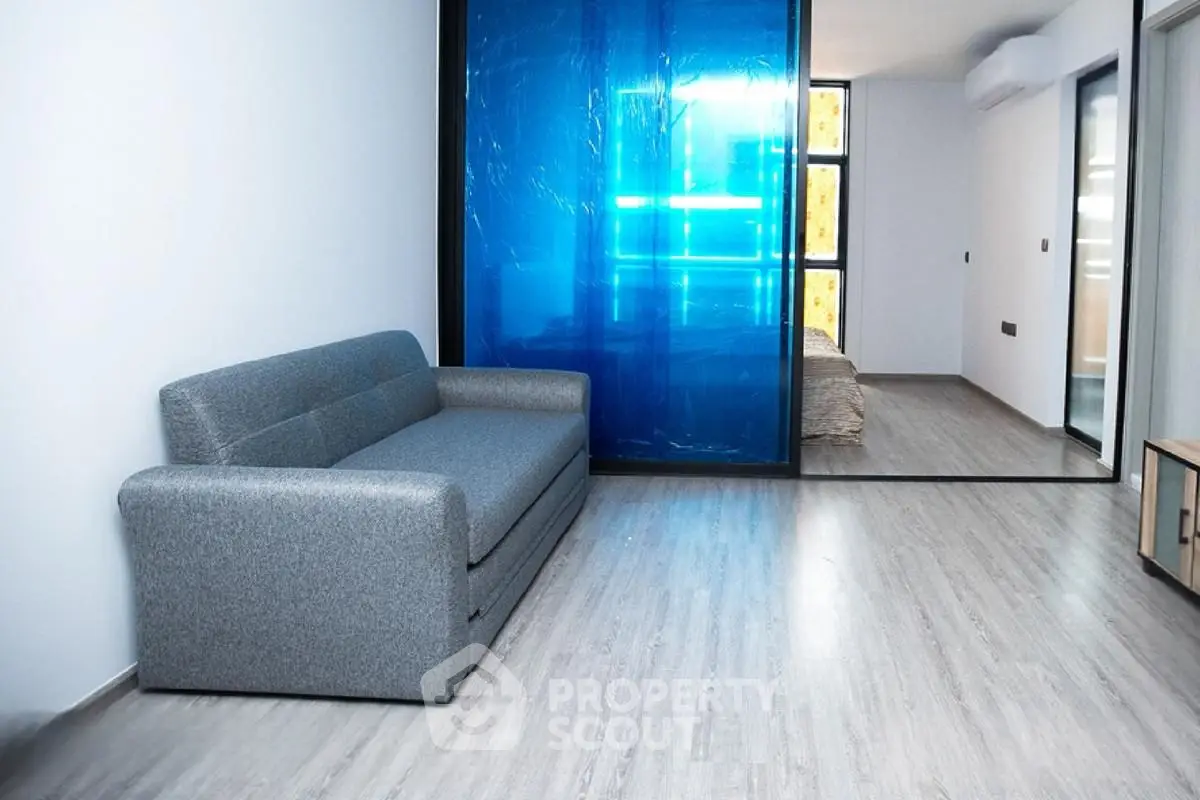 Modern apartment interior with sleek gray sofa and blue accent wall, showcasing minimalist design and open layout.