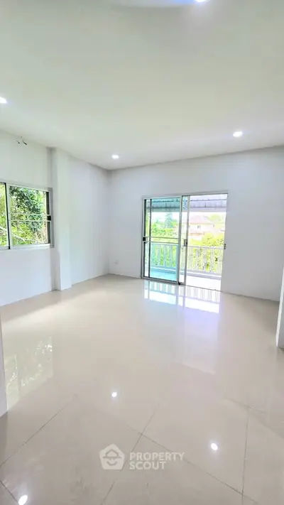 Spacious living room with large windows and balcony access, offering abundant natural light and serene views.