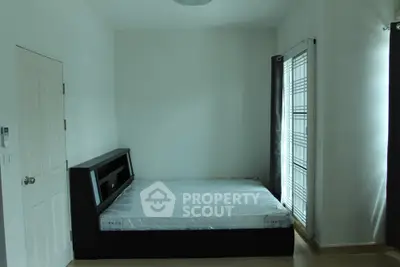 Spacious bedroom with modern bed and natural light from large window.