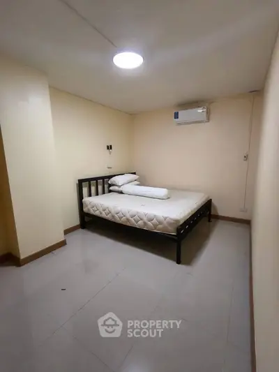 Minimalist bedroom with simple bed and air conditioning in a cozy apartment.