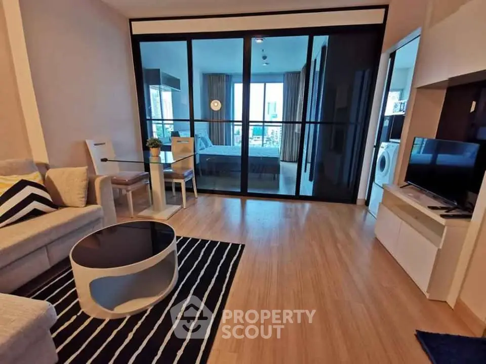 Modern living room with stylish furniture and view into bedroom, featuring sleek wooden flooring.