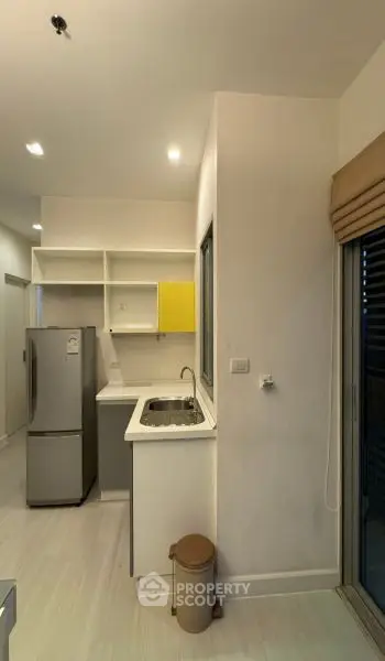 Modern kitchen with sleek design, featuring a stainless steel fridge and ample storage space.