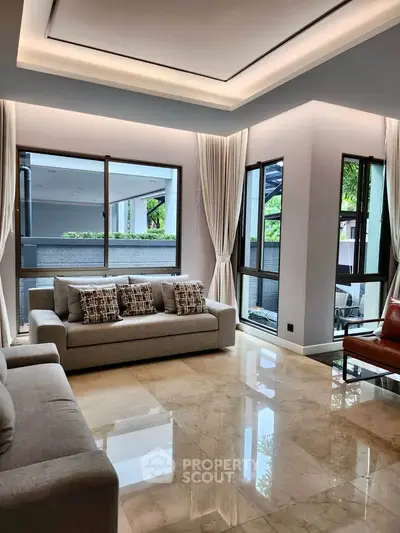 Luxurious living room with elegant sofas and large windows offering natural light and garden views.