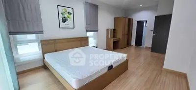 Spacious modern bedroom with wooden flooring and stylish decor in a contemporary home.