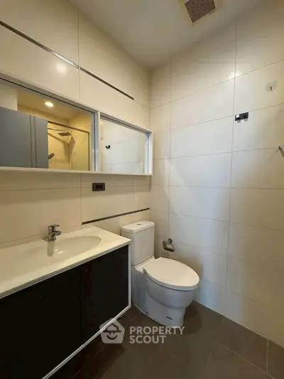 Modern bathroom with sleek fixtures and minimalist design, featuring a spacious shower and elegant vanity.