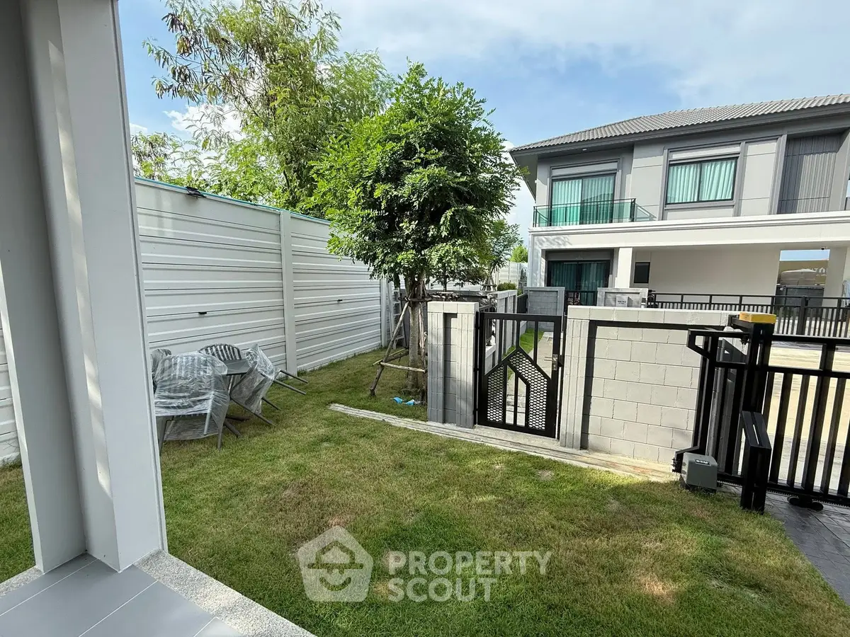 Charming backyard with lush lawn and modern fence, perfect for outdoor relaxation.