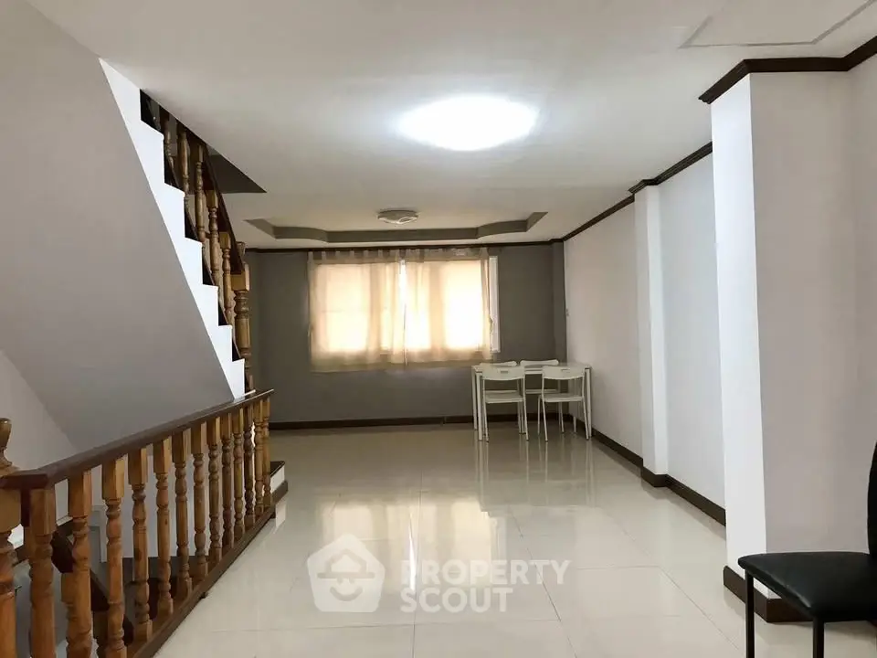 Spacious open-plan living area with modern staircase and natural light.