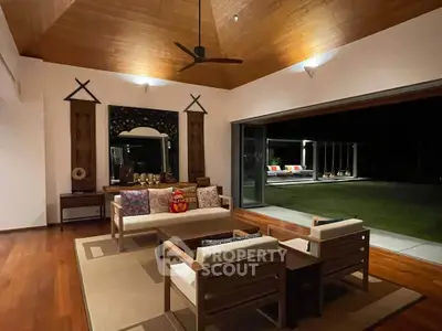 Luxurious open living room with wooden ceiling and garden view at night