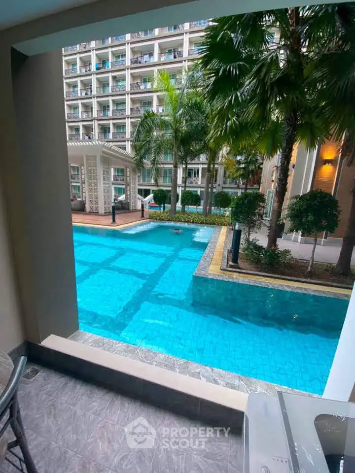 Luxurious poolside view from a modern apartment balcony with lush greenery and elegant architecture.