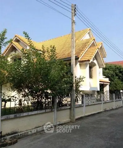 Charming suburban house with yellow tiled roof and lush greenery