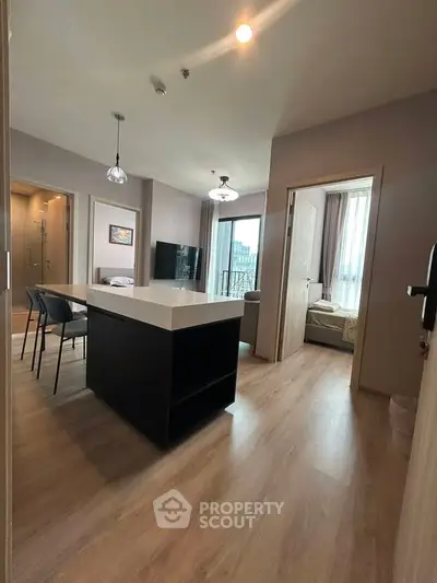 Modern apartment interior with open layout and stylish furnishings, featuring a kitchen island and large windows.