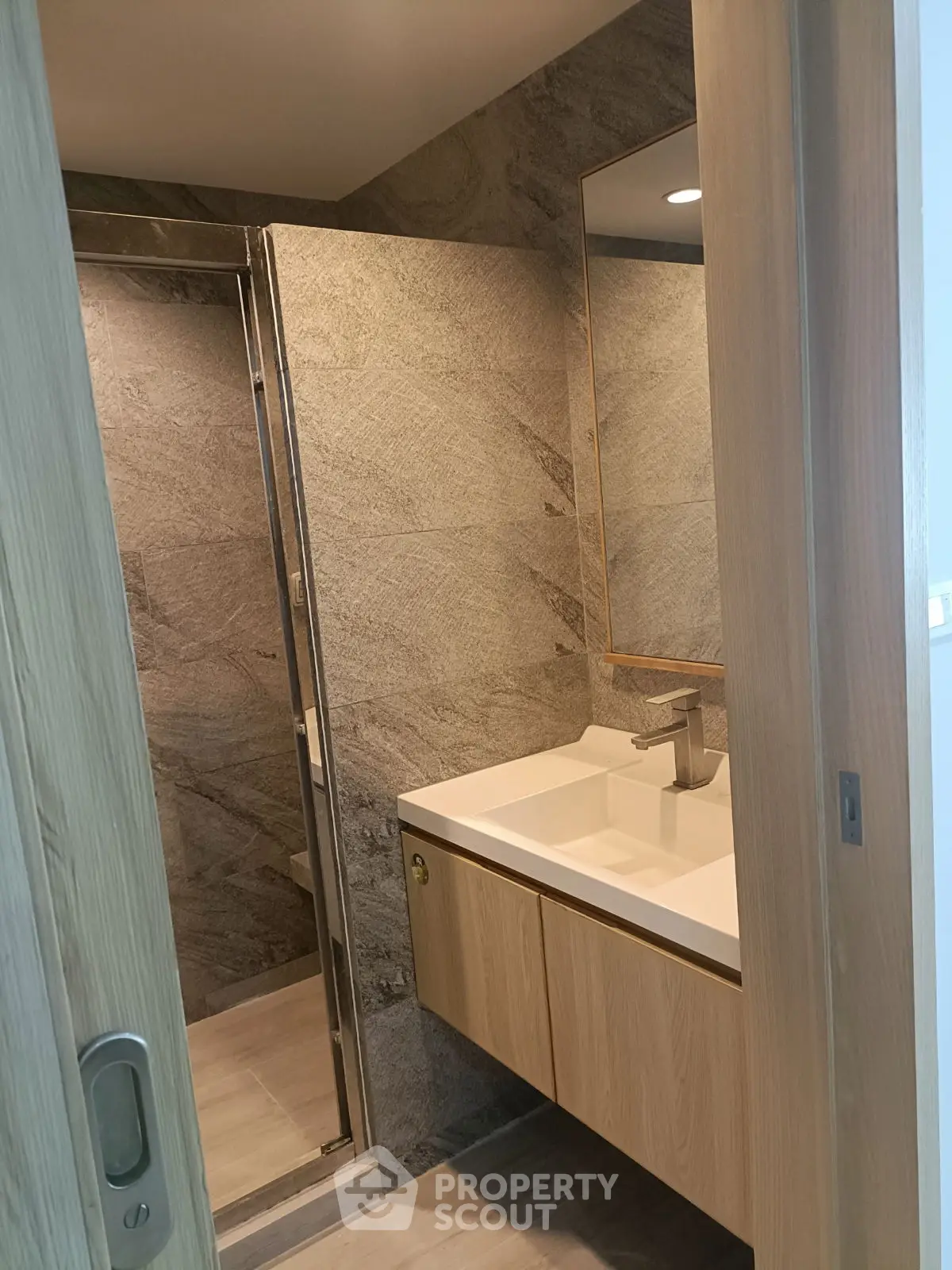Modern bathroom with sleek wooden cabinetry and stone tile walls