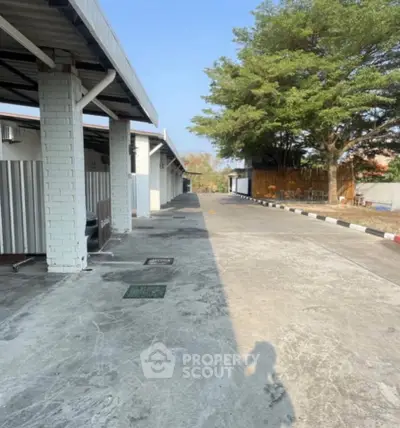 Spacious outdoor parking area with covered spaces and lush greenery, ideal for residential or commercial use.