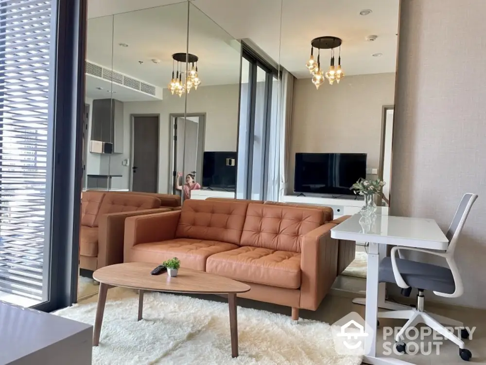 Modern living room with stylish furniture and large mirror wall enhancing space.