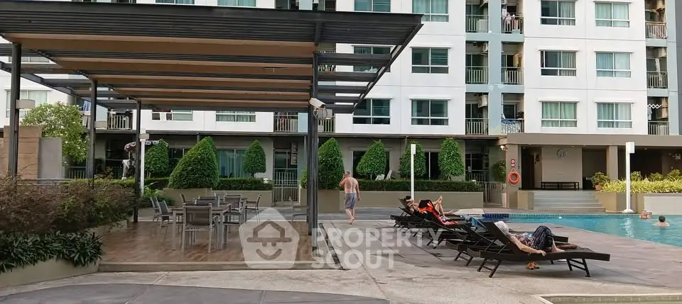 Modern apartment complex with poolside relaxation area and sun loungers.