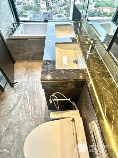 Luxurious bathroom with marble countertop and city view, featuring modern fixtures and elegant design.