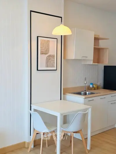Modern kitchen with white cabinets and dining area in cozy apartment