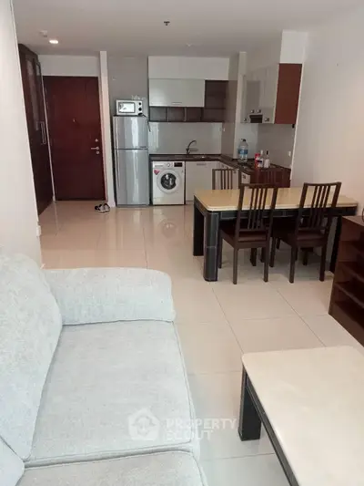 Modern open-plan living room with kitchen, featuring sleek furniture and appliances.
