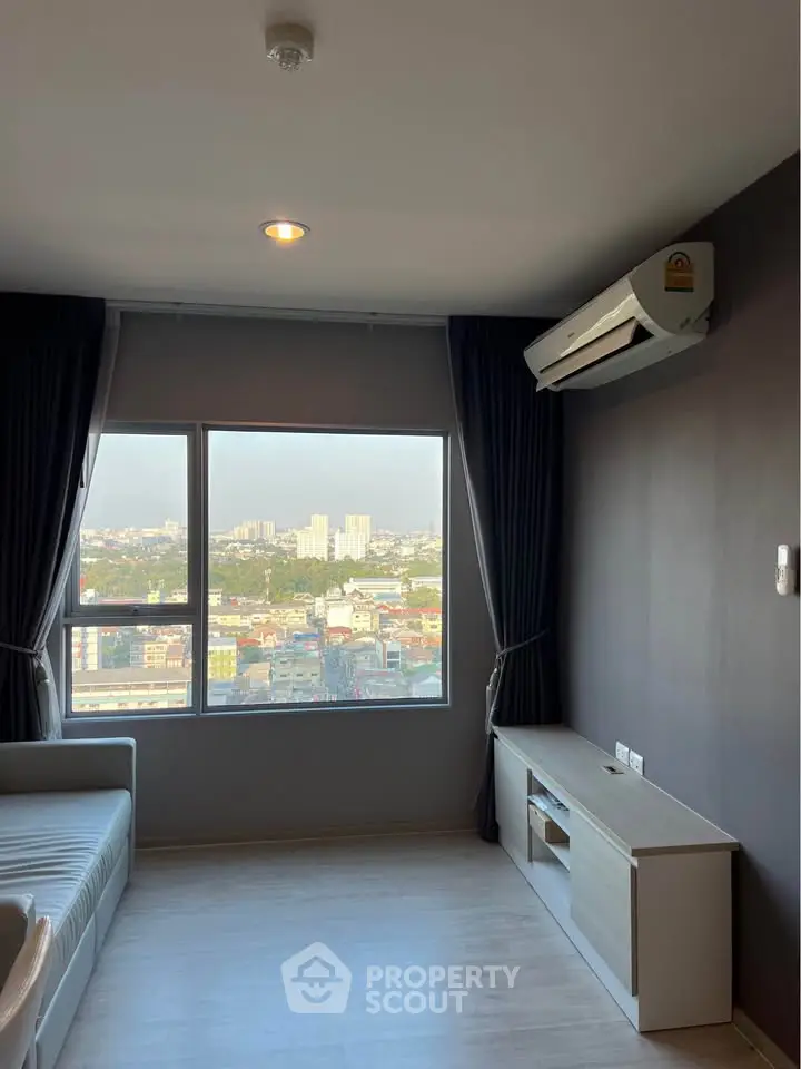 Modern living room with large window offering stunning city view, featuring sleek furniture and air conditioning.