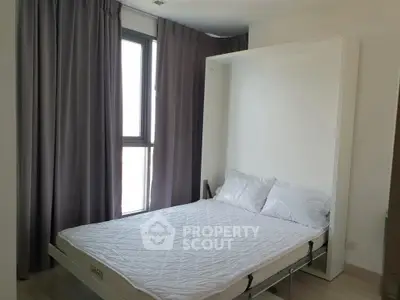 Modern bedroom with Murphy bed and large window for natural light.