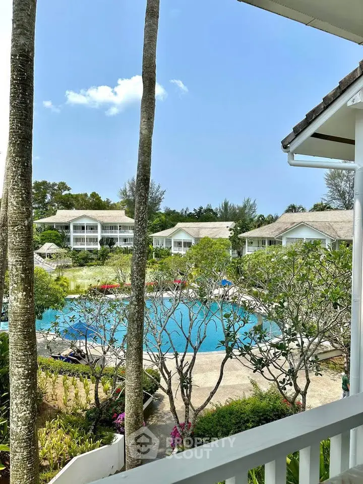 Stunning resort-style pool view from balcony with lush greenery and elegant architecture.