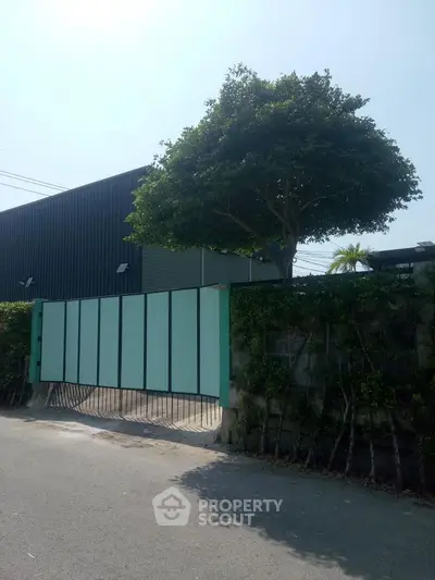 Modern building exterior with tall gate and lush tree