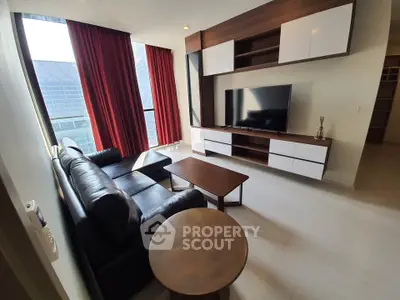 Modern living room with sleek furniture and large TV, featuring floor-to-ceiling windows and stylish decor.