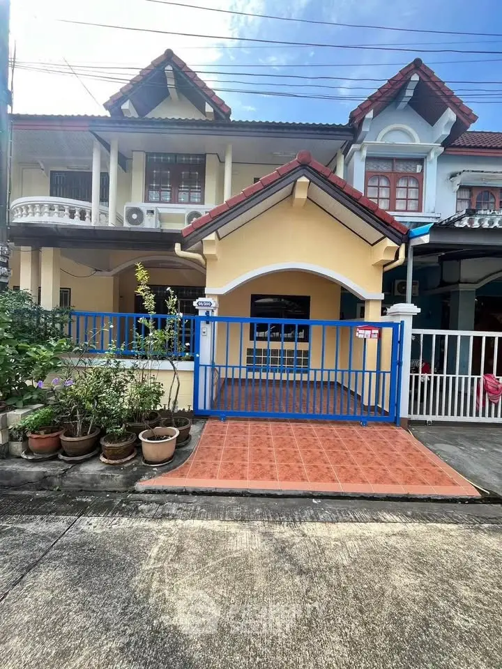 Charming townhouse with blue gate and tiled entrance in a serene neighborhood.