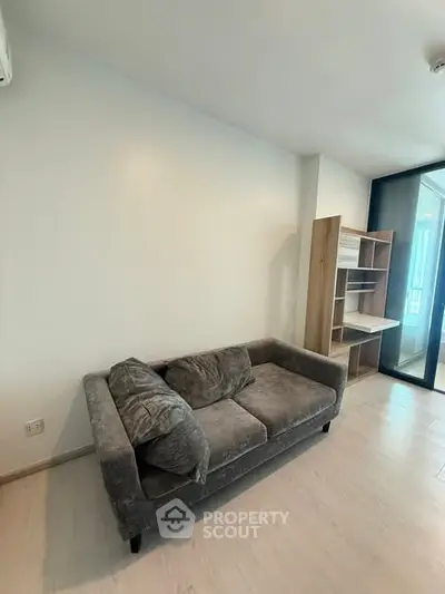 Modern living room with cozy gray sofa and sleek wooden shelving unit.