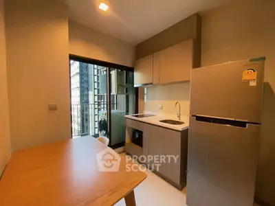 Modern kitchen with sleek cabinetry and stainless steel fridge in a cozy apartment setting.