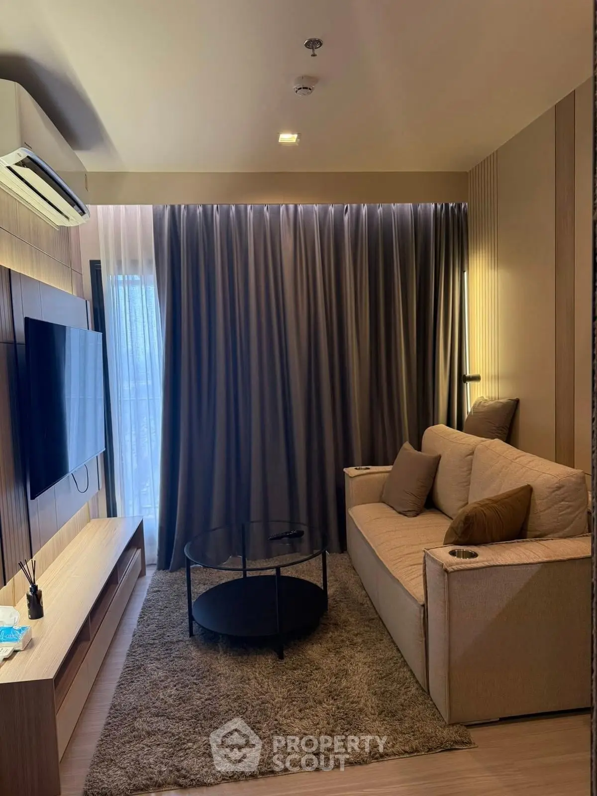 Cozy living room with modern decor, featuring a plush sofa, flat-screen TV, and elegant curtains.