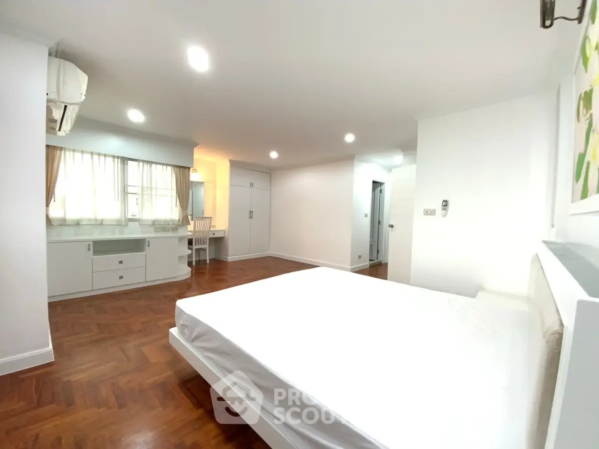 Spacious bedroom with hardwood floors and ample natural light
