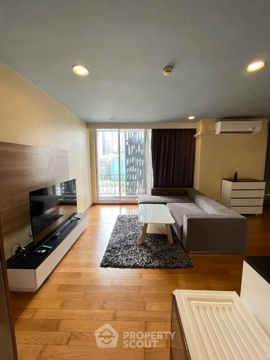 Modern living room with sleek furniture and city view, featuring a cozy gray sofa and stylish TV setup.