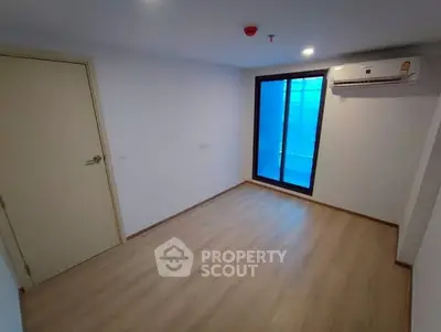 Spacious empty room with wooden flooring and large window