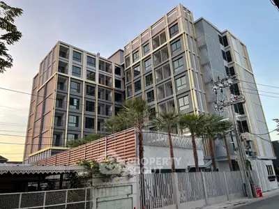 Modern multi-story residential building with contemporary design and palm trees in the foreground.